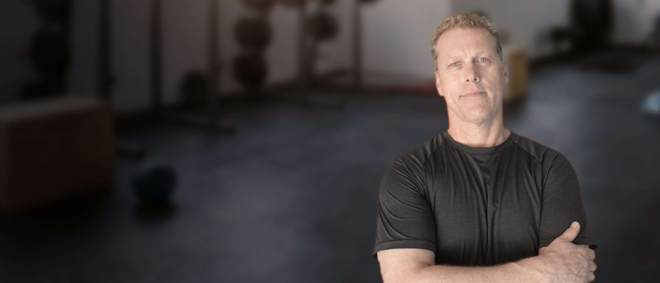 Randy Ehrler, movement coach for adults over 40, arms crossed in his gym